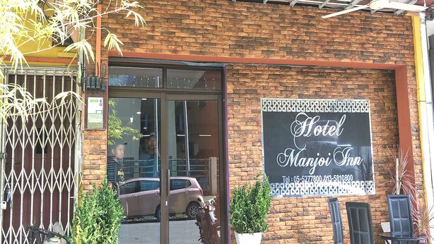 Een hotel ingang met een glazen deur, een bord en terrasplekken.
