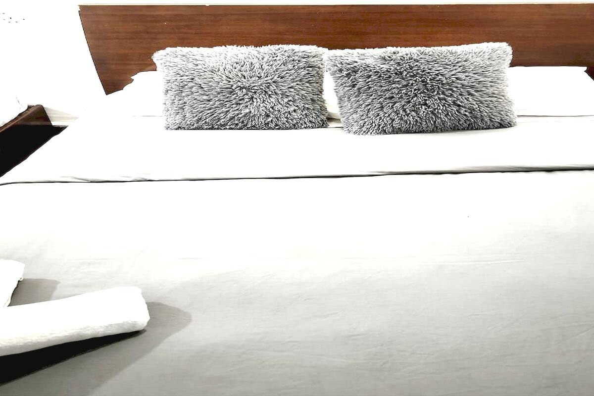 Ein ordentlich bezogenes Bett mit zwei flauschigen Kissen und einer weißen Decke.