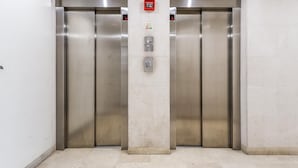 An elevator with metallic doors and a control panel with emergency buttons.