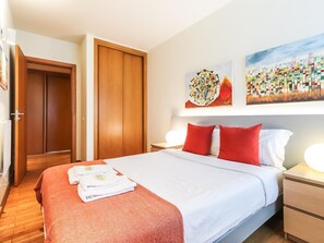 A hotel room with a bed, two nightstands, a wooden wardrobe, and two wall art pieces.