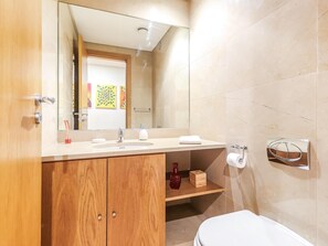A modern bathroom with a wooden vanity, a large mirror, a sink, and a toilet.