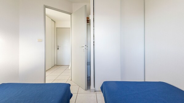 A room with two beds, a door leading to another room, and a tiled floor. - Apartment, pool, free parking (Agde)