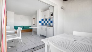A compact room with a kitchenette, a dining table, a sofa, and a small window. - Apartment Cap d'Agde, pool, private parking (Agde)