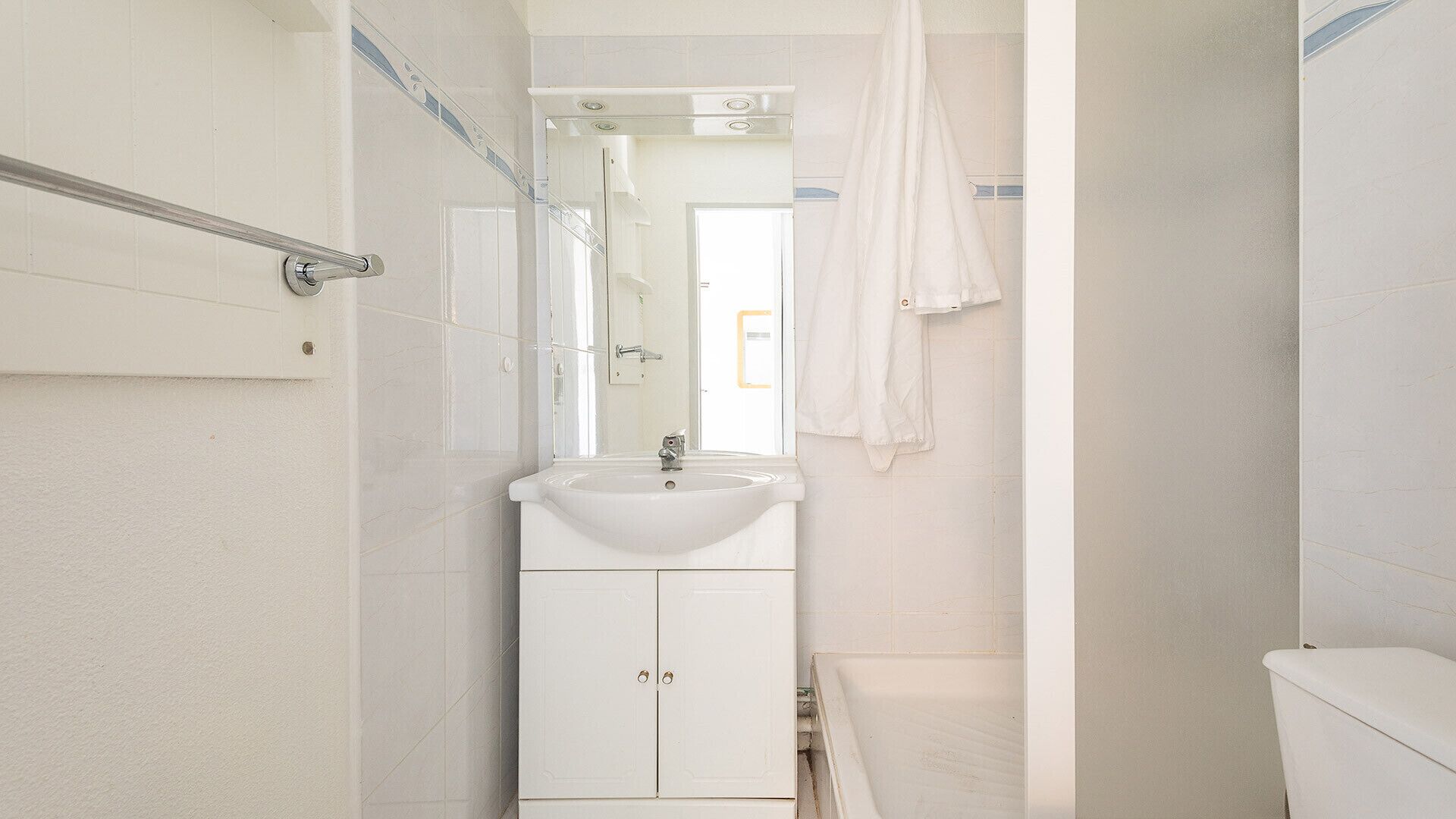 Une salle de bain avec un lavabo blanc, un miroir et une douche.