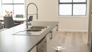 Een moderne keuken met een roestvrijstalen spoelbak, een afwasschaal en een inbouw vaatwasser.