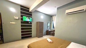 Ein Schlafzimmer mit Bett, Wandfernseher, Kleiderschrank und Schreibtisch mit Stuhl.
