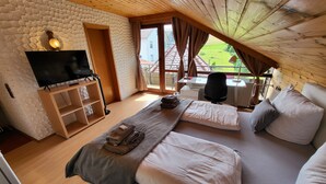 Een slaapkamer met een houten plafond, een televisie, een bureau en een bed met kussens en dekbed.