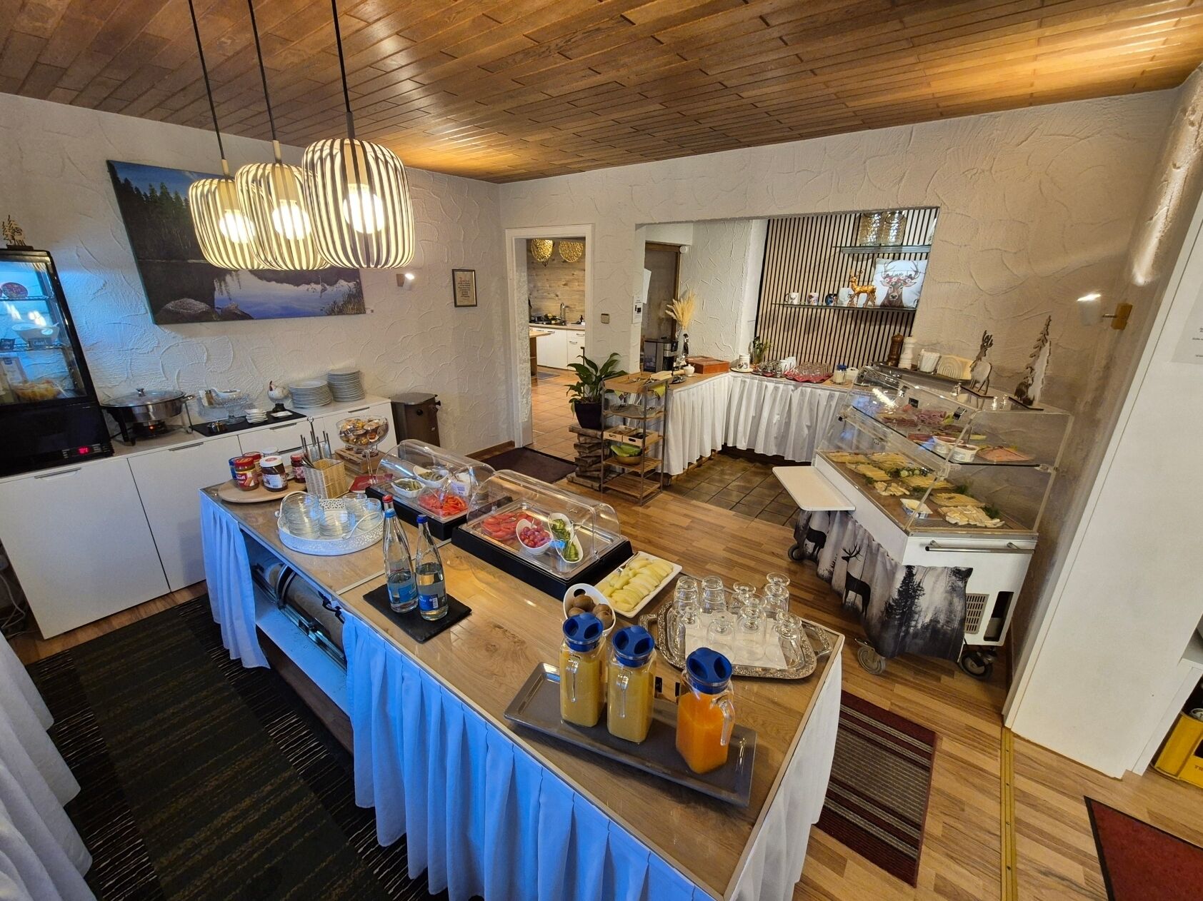 Ein Frühstücksbuffet mit verschiedenen Speisen und Getränken, eine Küchenzeile und ein Essbereich mit Blick.