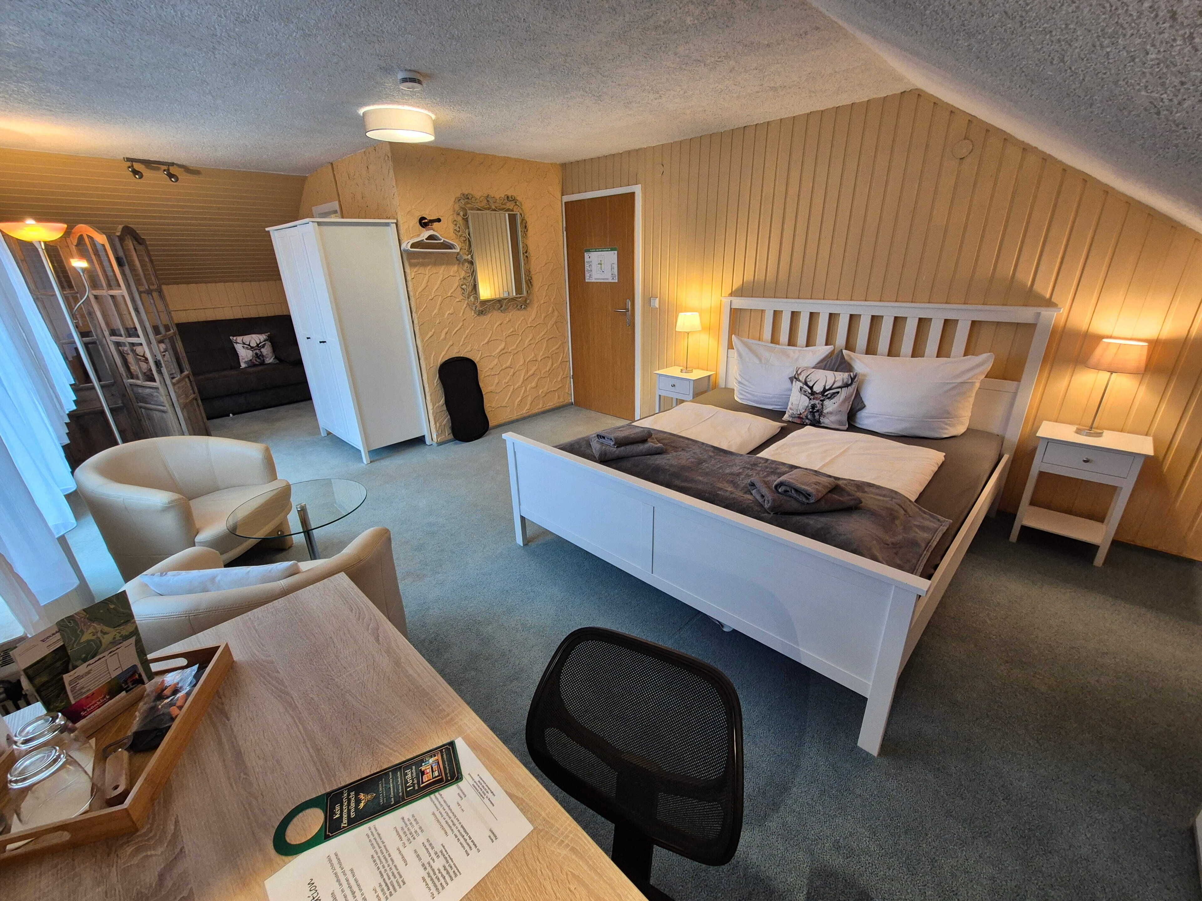 Una habitación de hotel con cama, escritorio, silla, mesita y lámpara.