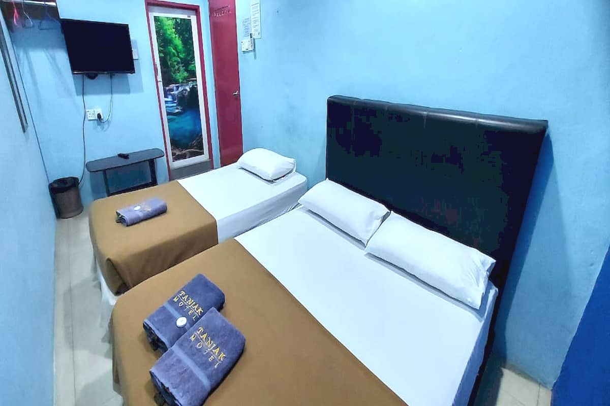 A hotel room with two beds, a TV, and a door with a poster.