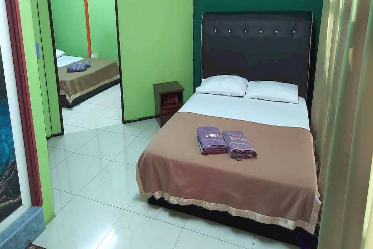A hotel room with a bed, a nightstand, and a mirror.