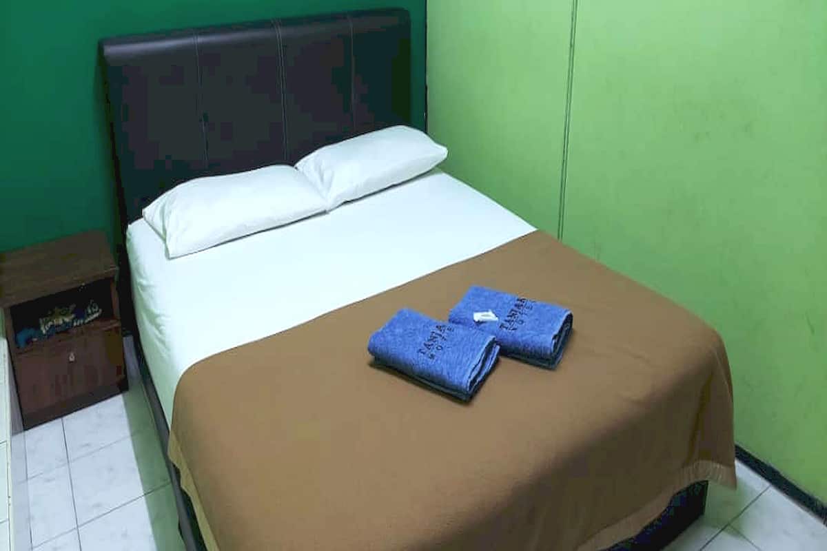 A single bed with a brown bedspread and two folded towels.