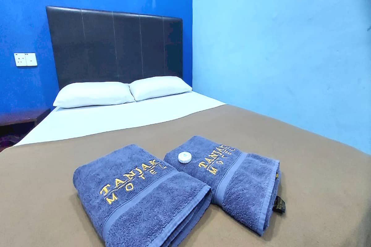A bed with two towels and a headboard in a room with blue walls.