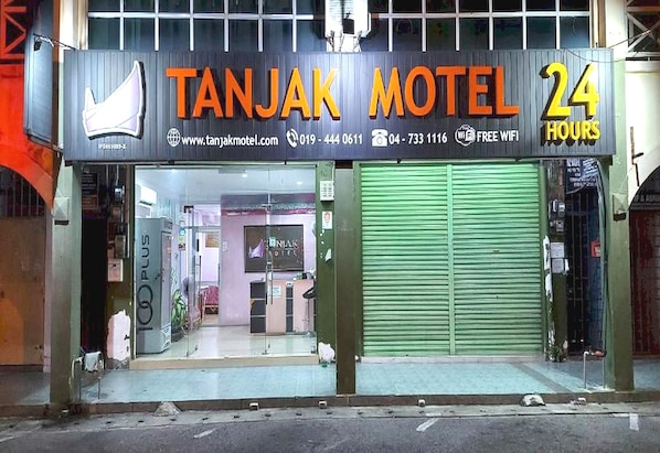 A hotel named Tanjak Motel with a 24-hour service sign.