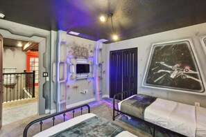 Un dormitorio con temática de Star Wars, que incluye arte en las paredes y una lámpara de techo.