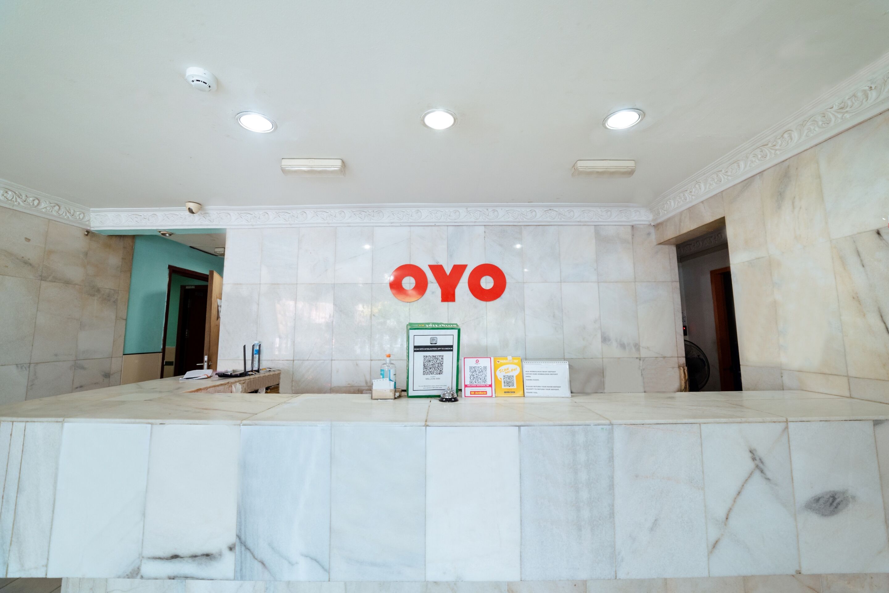 A reception desk with a marble counter, a "OYO" sign, and a QR code for check-in.
