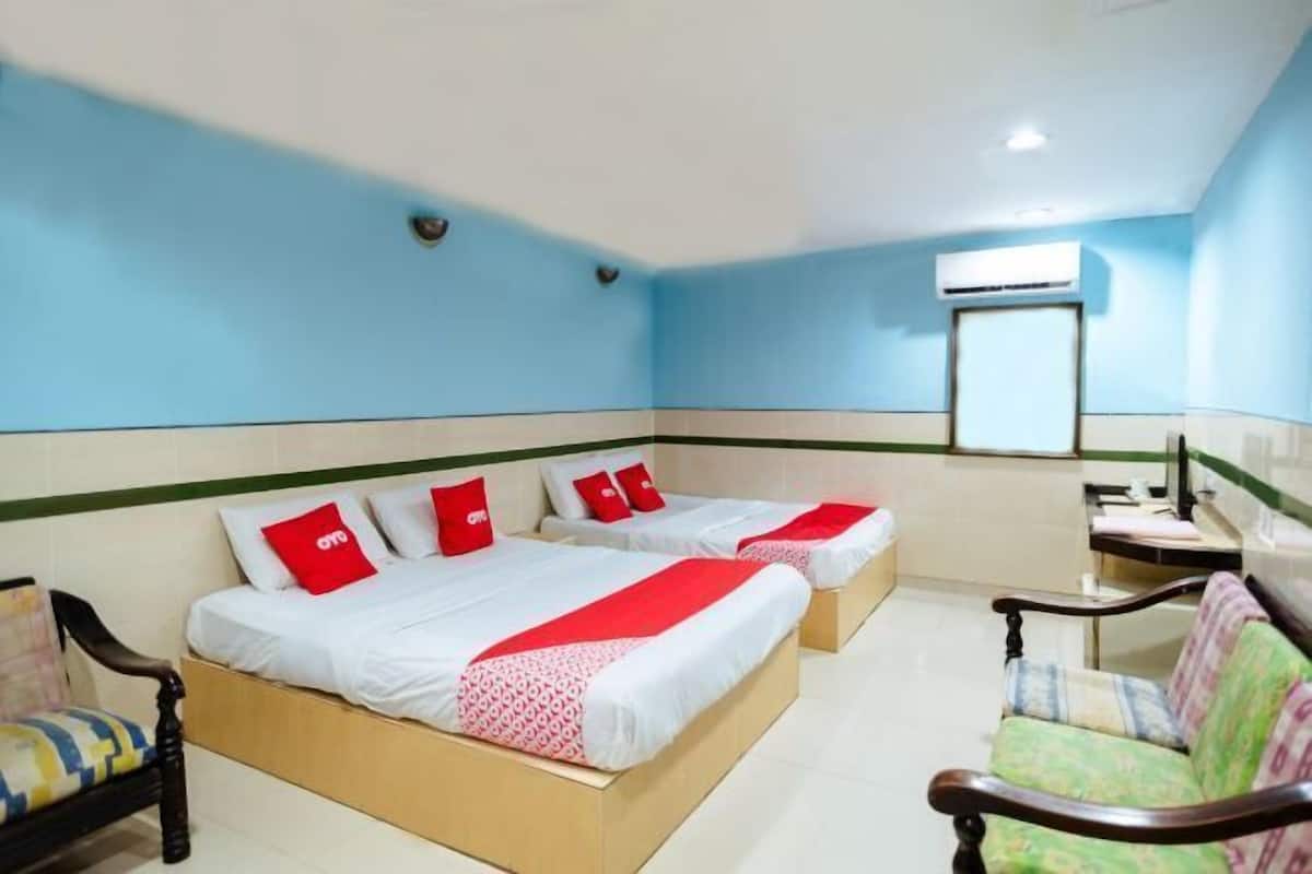 A hotel room with two beds, a desk, a chair, and an air conditioning unit.