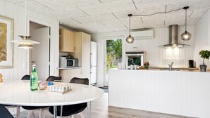 Una cocina moderna con armarios blancos, una isla central e iluminación colgante.