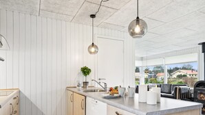 Una cocina moderna con una isla central, muebles blancos y vistas al exterior.