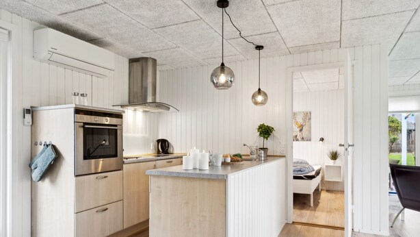 Una cocina moderna con armarios de madera, horno empotrado e iluminación colgante.
