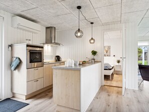 Een moderne keuken met houten kastjes, een inbouwoven en hanglampen.