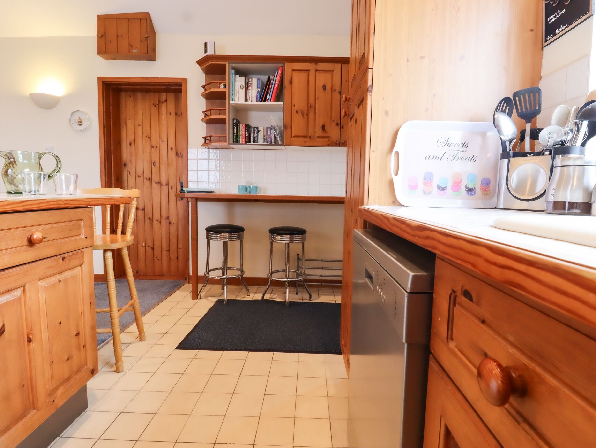 Una cocina con armarios de madera, una encimera, una cafetera y una estantería.