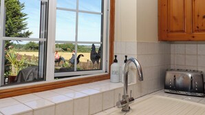 A kitchen with a window, a stainless steel sink, a toaster, and wooden cabinets. - The View (Faversham)