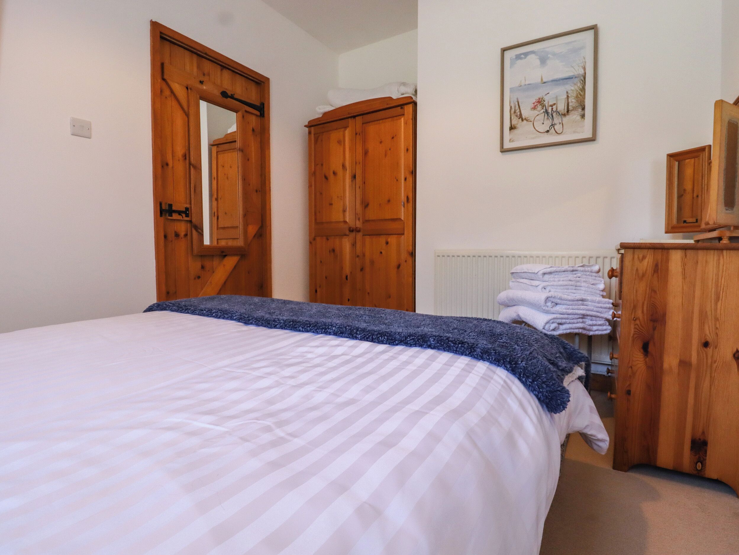 Ein Schlafzimmer mit Bett, Holzschrank und einem Bild an der Wand.