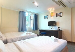 Une chambre d’hôtel avec deux lits, un bureau avec une chaise, une télévision et une fenêtre avec des rideaux.