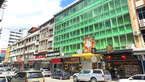 Un edificio con varias fachadas, que alberga un hotel y una agencia inmobiliaria.