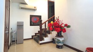 Una escalera con baranda de madera, dispensador de agua y un jarrón con flores rojas.