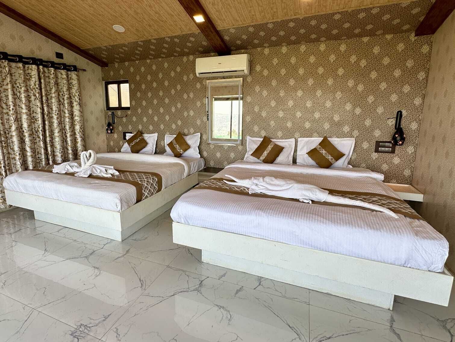 Une chambre d’hôtel avec deux lits, une grande fenêtre, un papier peint à motifs et un sol carrelé.