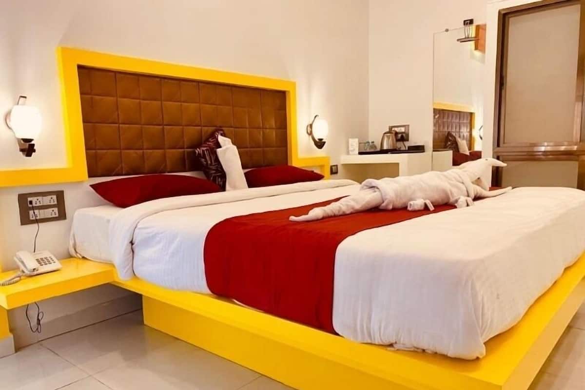 A modern hotel room with a large bed, yellow accents, a telephone, and a mirror.