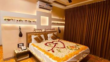 A bedroom with a bed, a ceiling fan, an air conditioning unit, and a 'Happy Anniversary' sign.