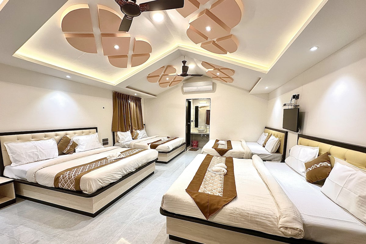 A hotel room with two large beds, a ceiling fan, a TV, and a bathroom visible through an open door.