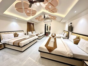A hotel room with two large beds, a ceiling fan, a TV, and a bathroom visible through an open door. - Hollywood Palace Resort (Mahabaleshwar)