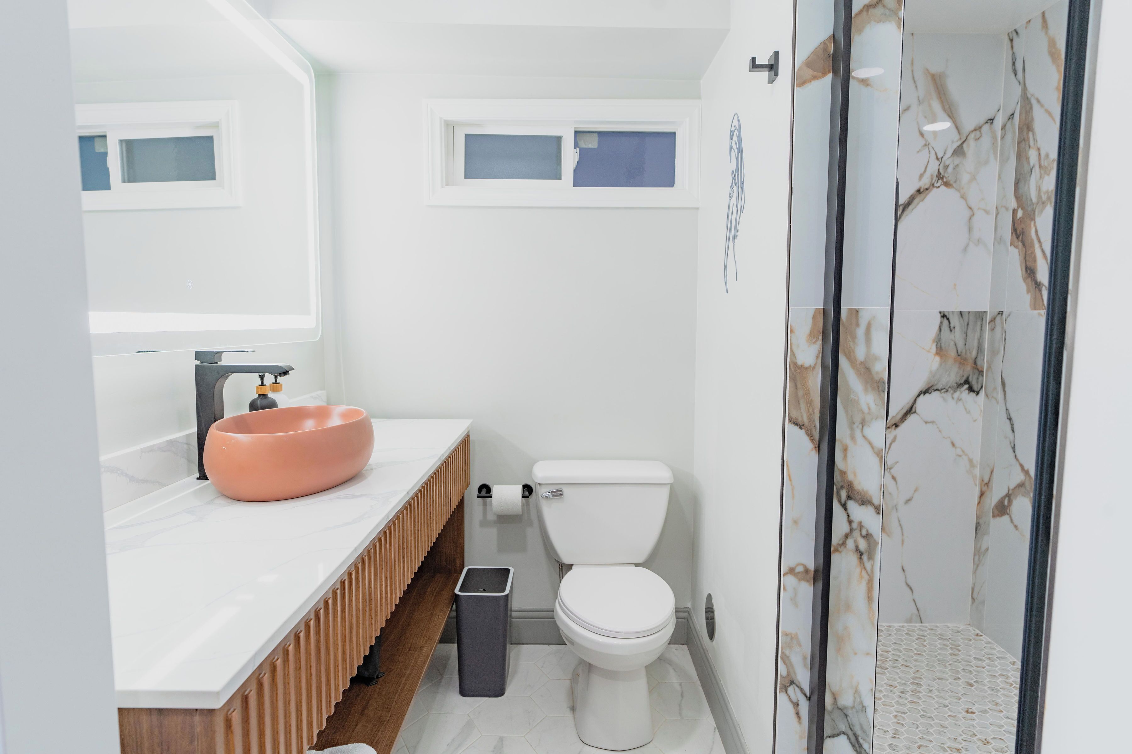 Et moderne badeværelse med en hvid vask, toilet og bruseområde.