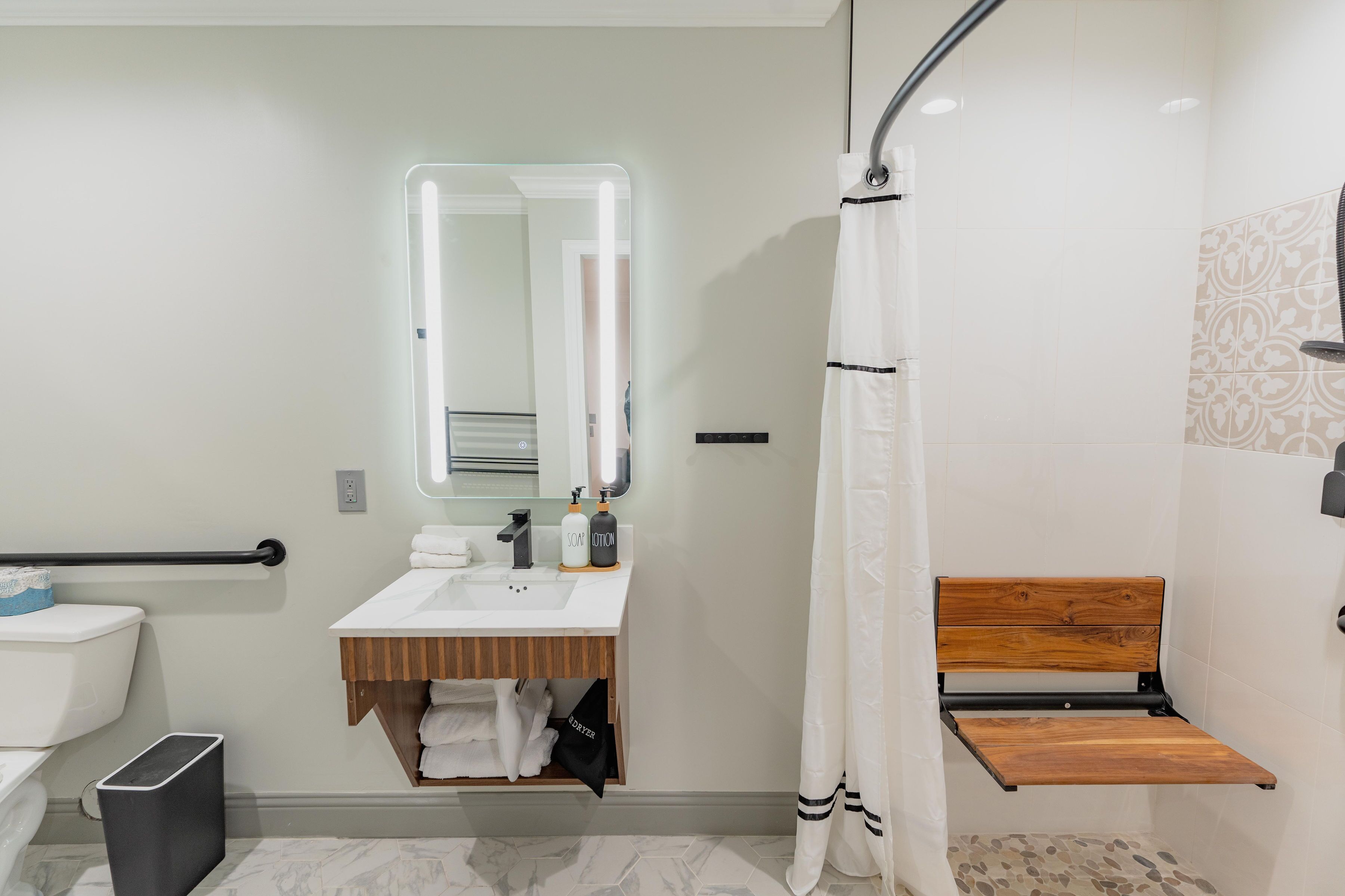 A modern bathroom with a white sink, mirror, and shower curtain.