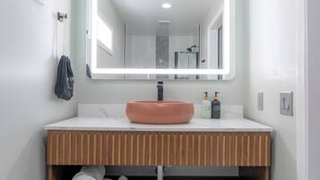 Uma casa de banho moderna com toucador branco, um espelho grande e pavimento em azulejos hexagonais.