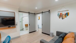 Una sala de estar moderna con un sofá gris, un sillón azul y un televisor montado en la pared.