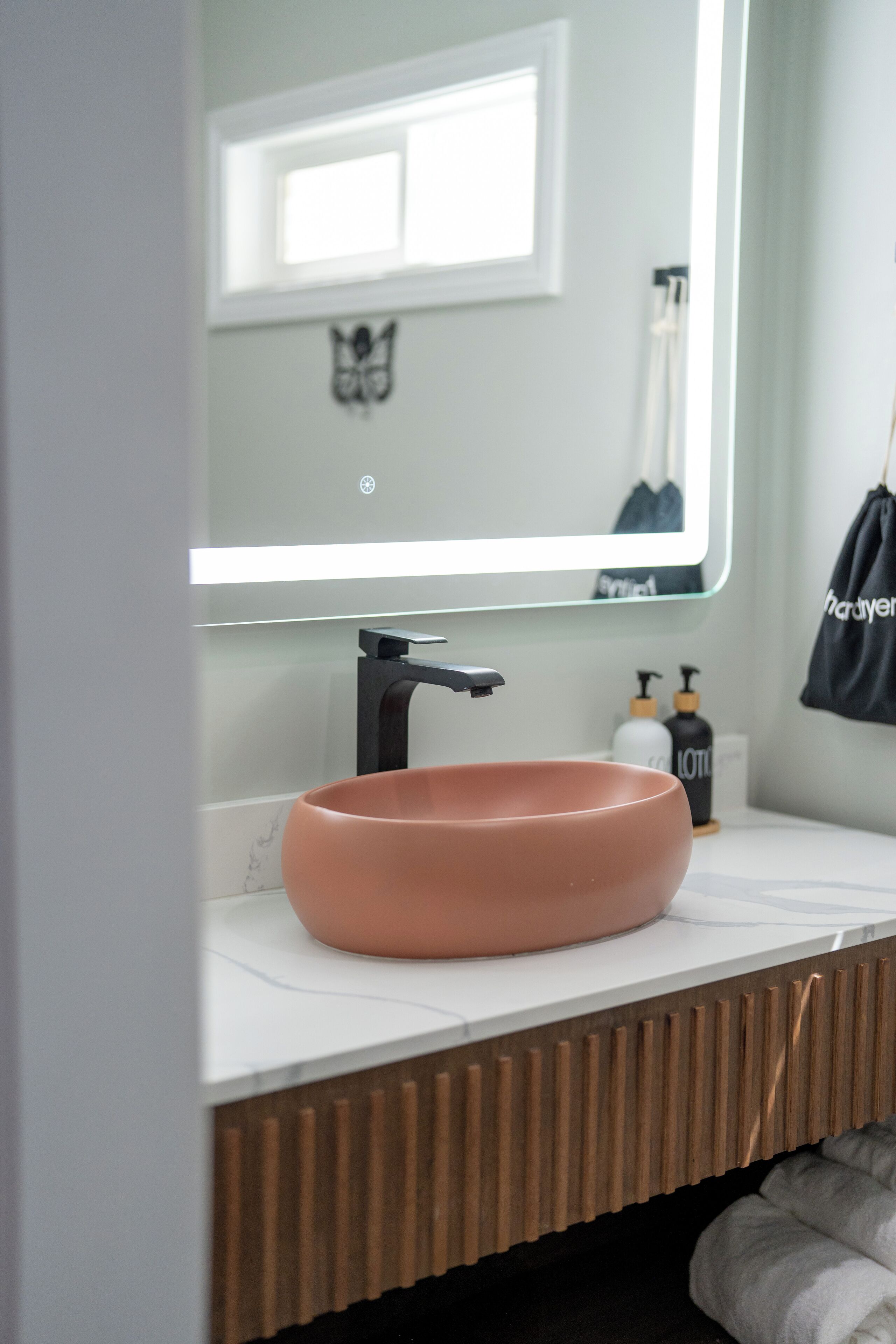 A bathroom with a modern sink, a large mirror, and a towel hanging on a rack.
