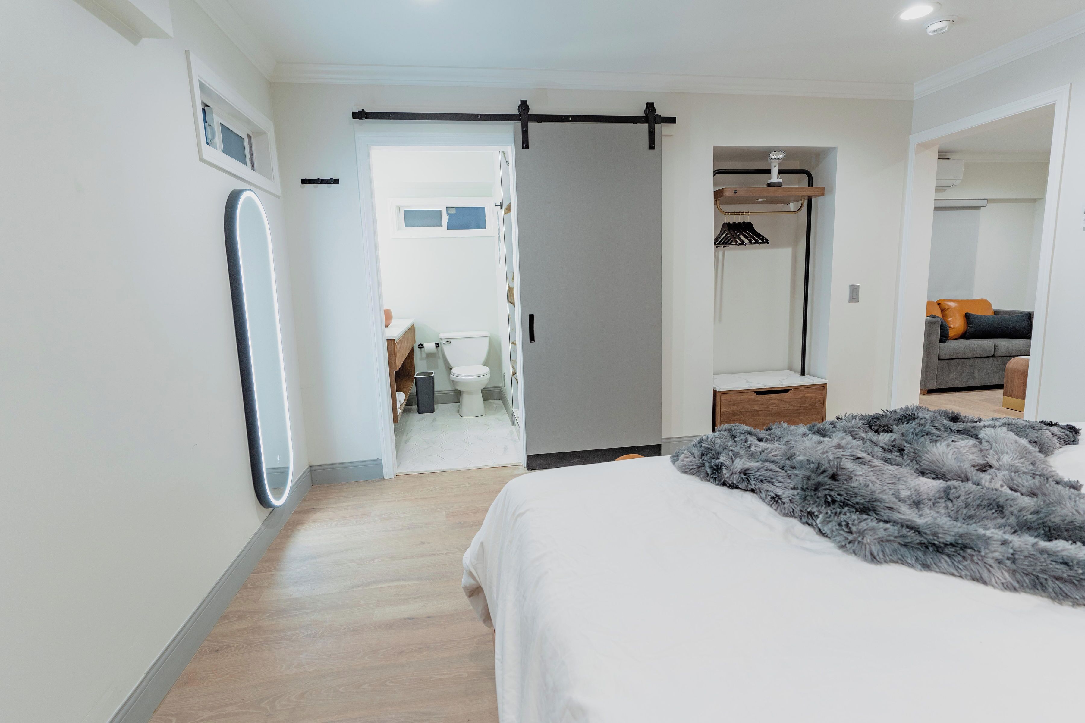 Un dormitorio moderno con una cama grande, un vestidor y un baño visible a través de una puerta abierta.
