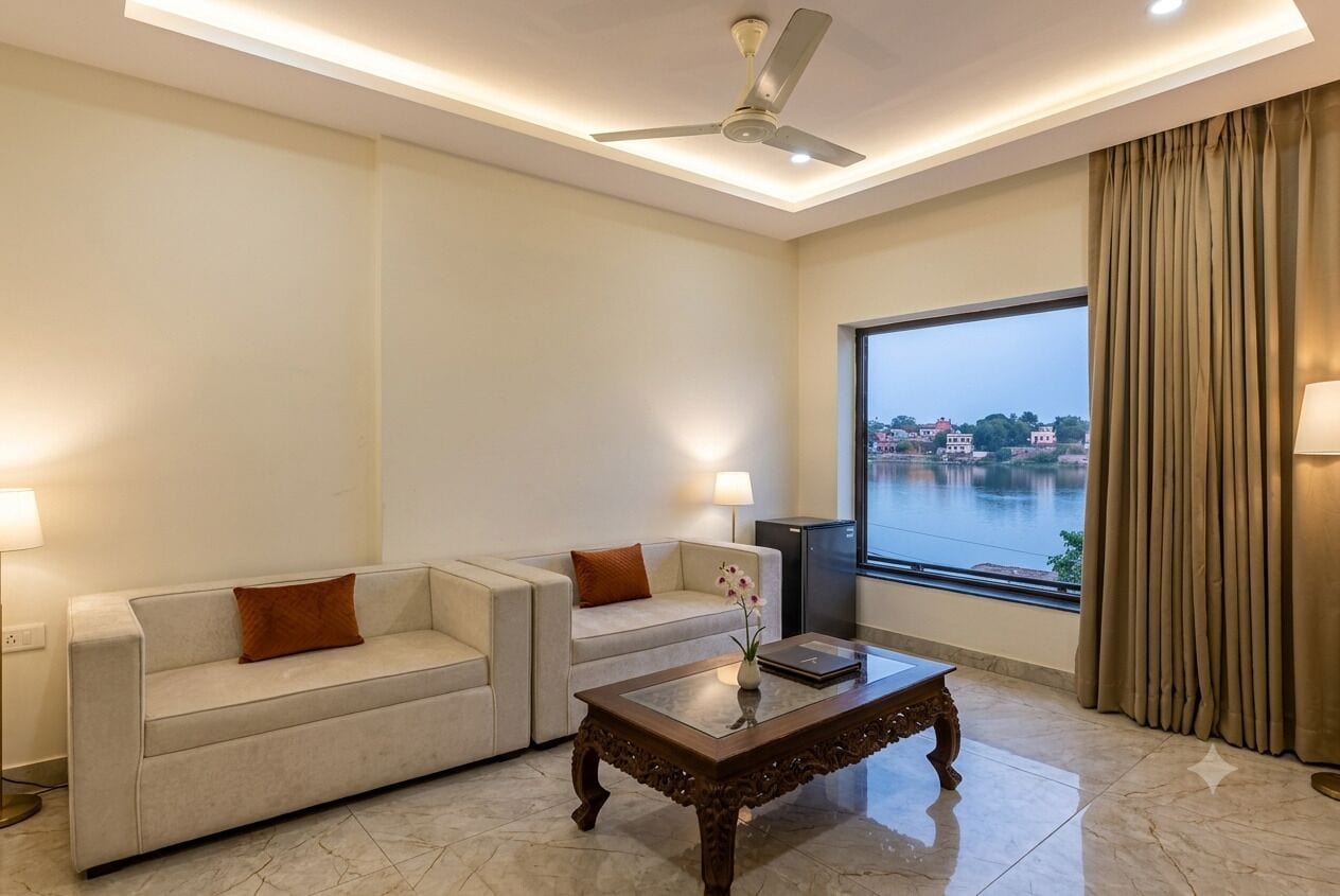 A modern living room with two sofas, a coffee table, a ceiling fan, and a large window with a view of a body of water.