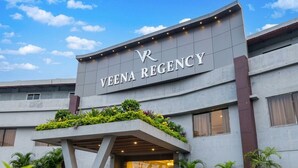 A building with a sign reading 'VENA REGENCY' and a covered entrance area with potted plants. - VEENA REGENCY (Chas)