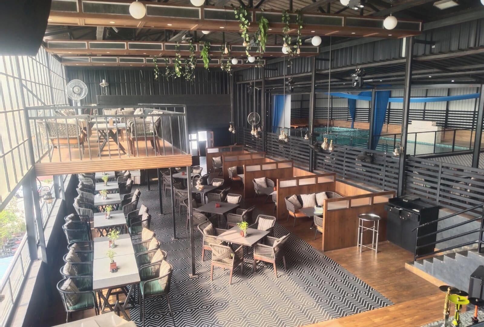 A spacious restaurant with high ceilings, hanging plants, and a mix of seating arrangements including tables and booths.