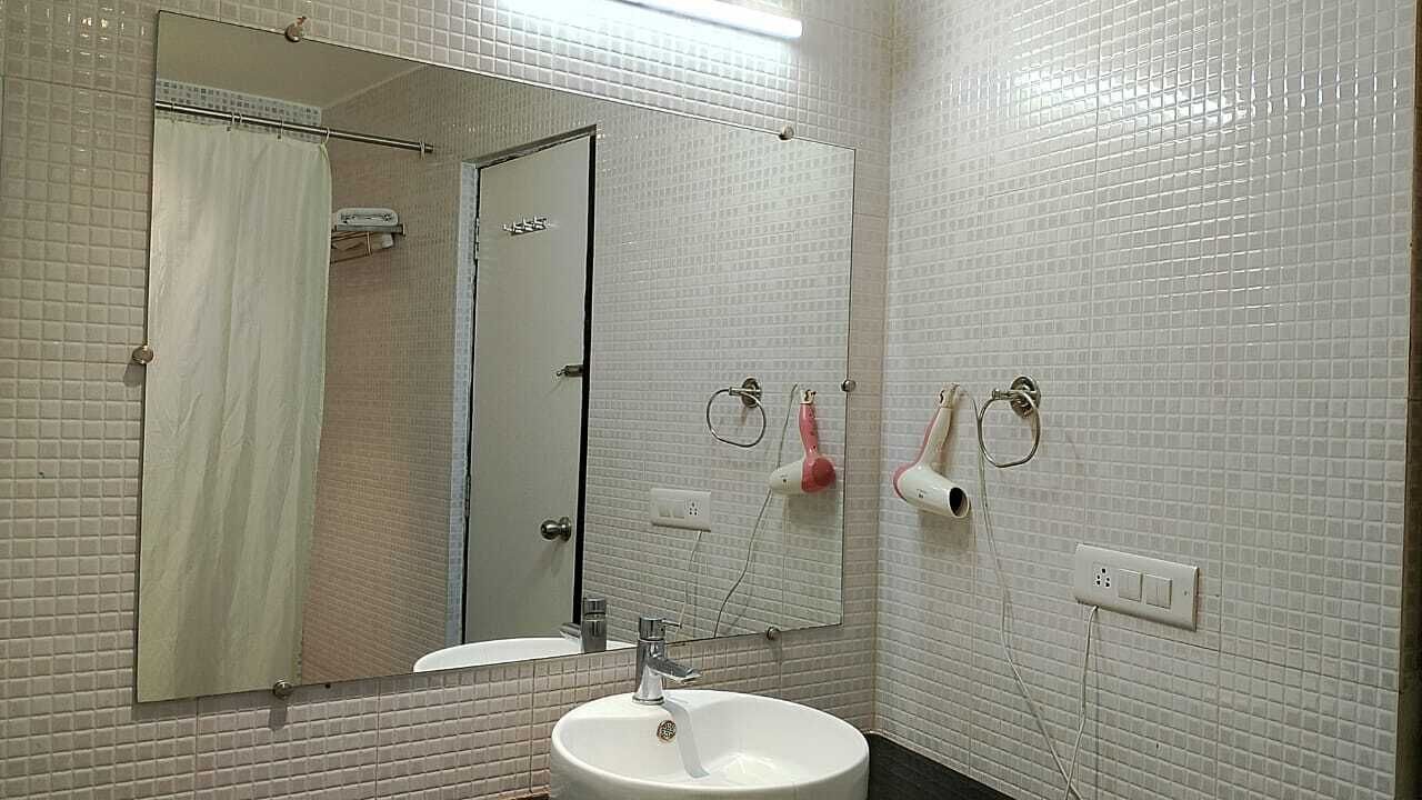 Ein Badezimmer mit Waschbecken, Spiegel, Duschvorhang und Handtuchhalter.
