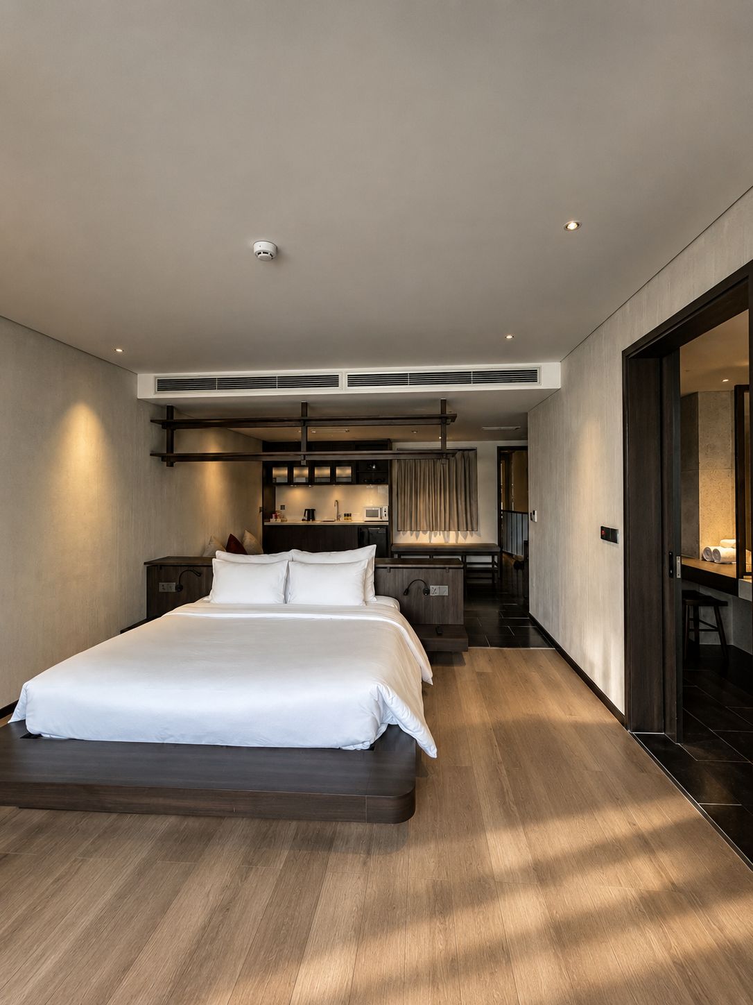 A modern hotel room with a large bed, a desk, and a seating area.