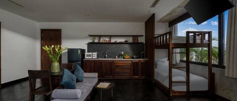 A modern living room with a sofa, a dining table, and a kitchen area.