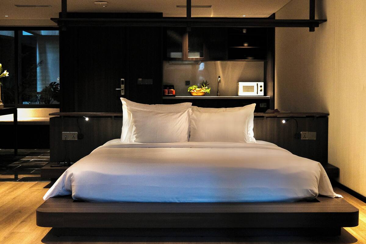 Une chambre d’hôtel moderne avec un grand lit, une petite kitchenette et une vue sur l’extérieur.