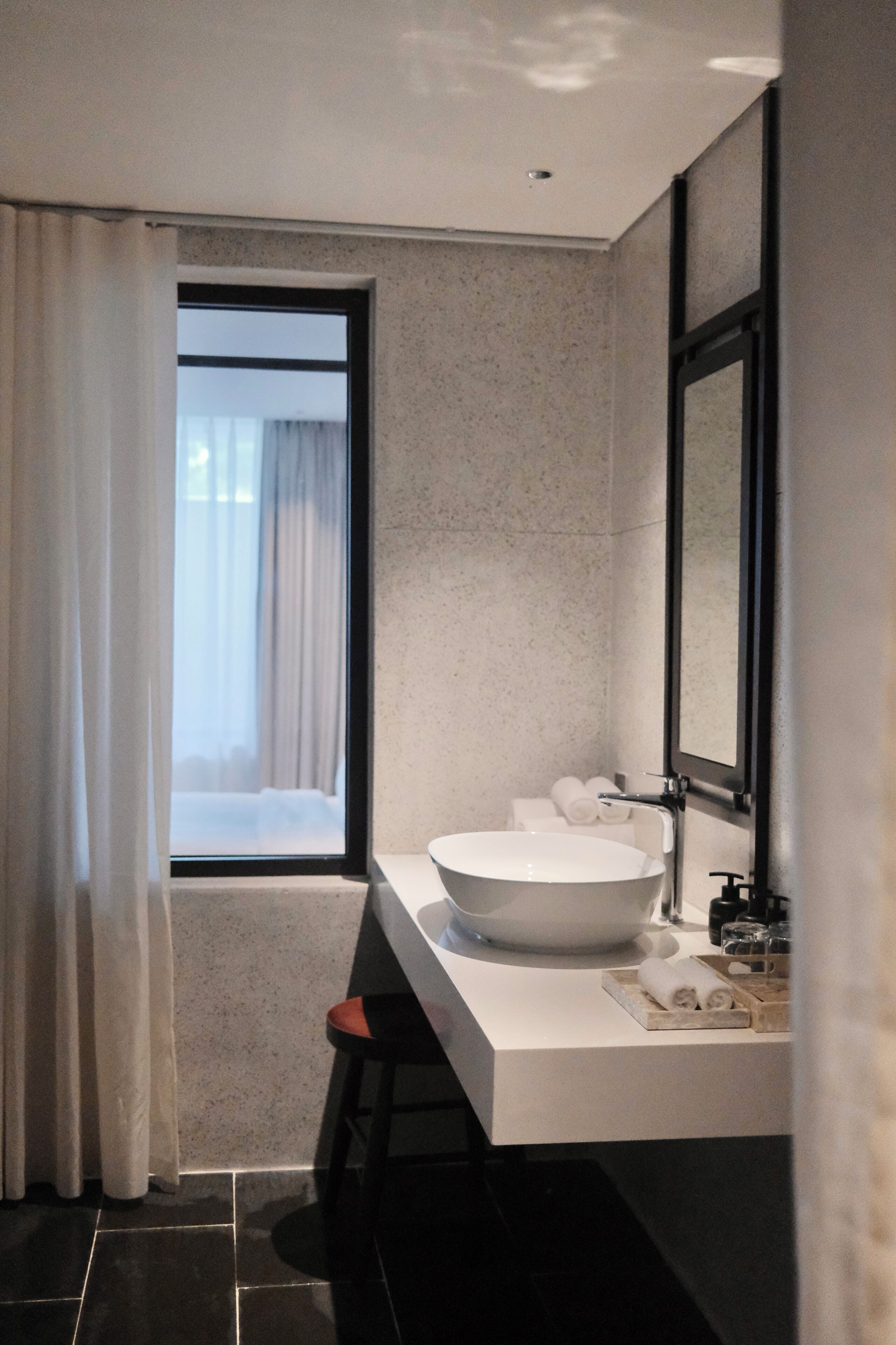 A modern bathroom with a large window, a white sink, and a mirror.